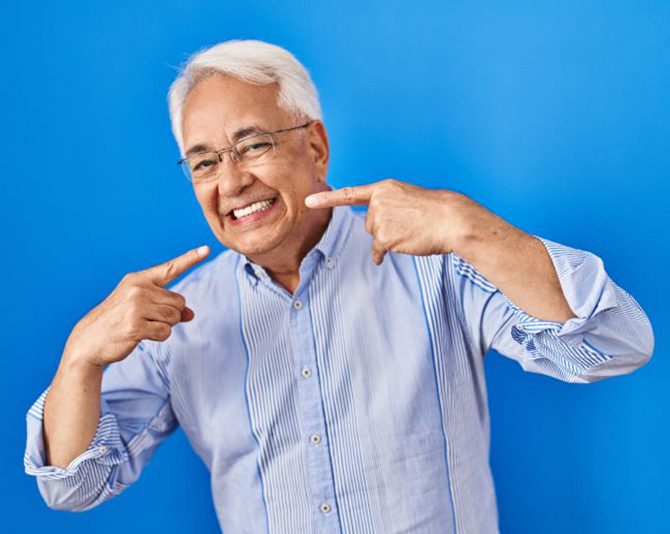 Confident senior man pointing at his dentures
