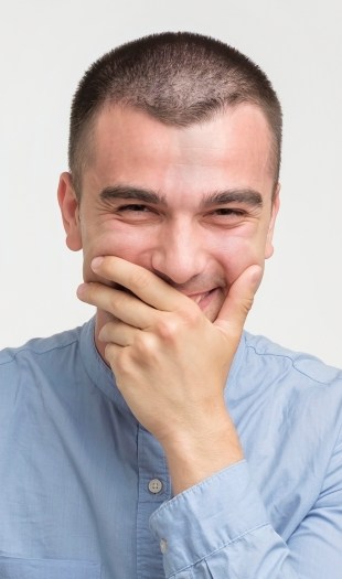 Laughing man covering his smile with his hand