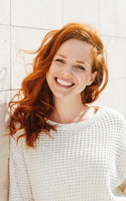 Woman smiling by a wall
