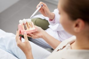 Woman looking at dental implant model during her consultation