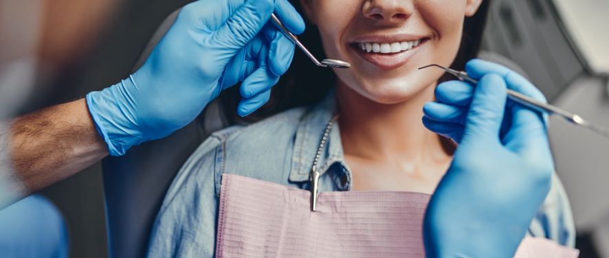 Dentists' hands holding instruments over patient's smile