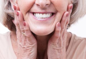 Senior woman smiling and showing off bright, white dentures.